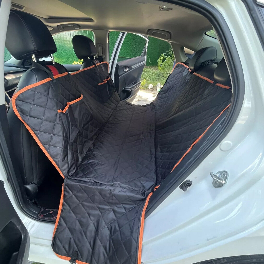 Black waterproof dog car seat hammock with orange trim fitted across a car’s rear seats